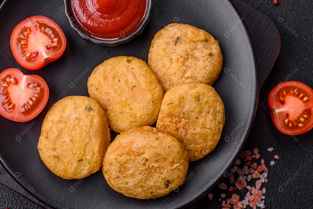 Peixe redondo ou pepitas de frango com sal e especiarias empanadas sobre um fundo escuro de concreto