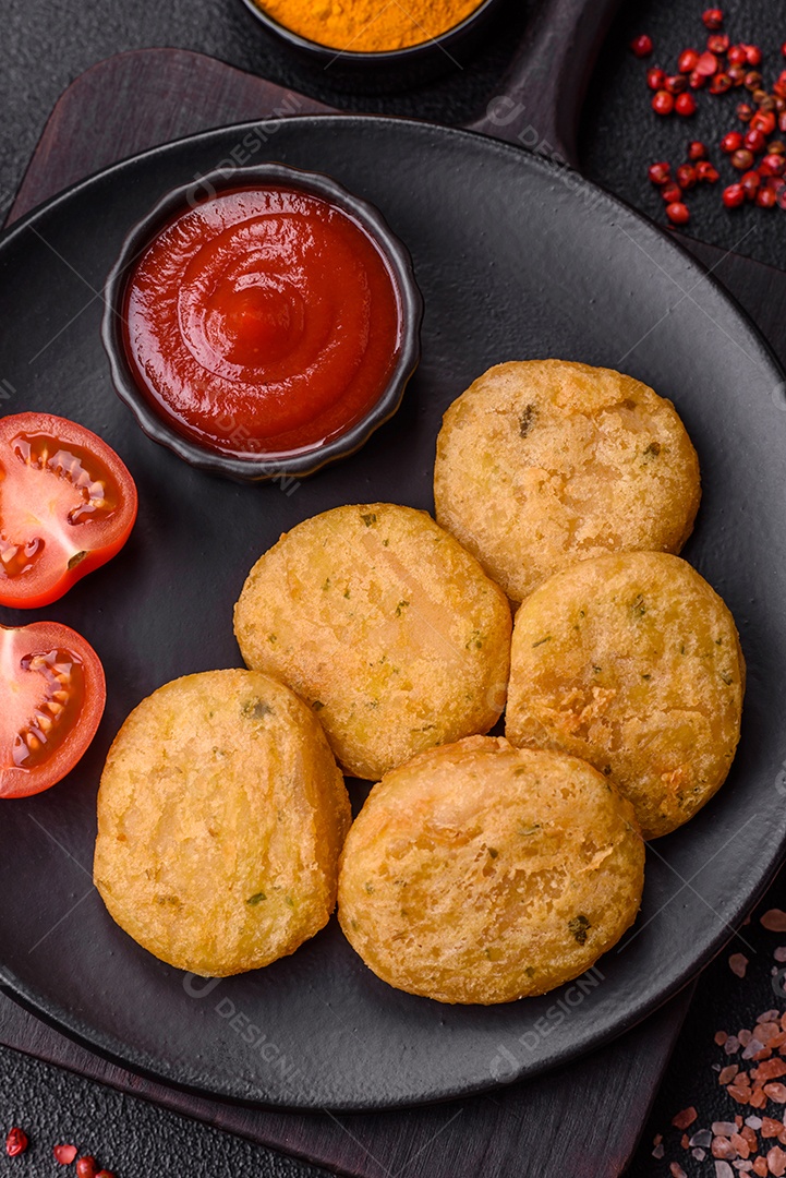 Peixe redondo ou pepitas de frango com sal e especiarias empanadas sobre um fundo escuro de concreto