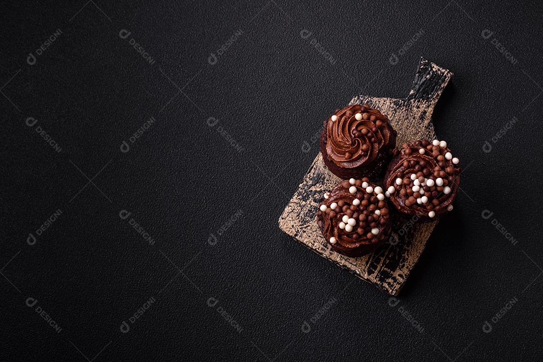 Deliciosos muffins frescos com recheio e cobertura de chocolate sobre um fundo escuro de concreto