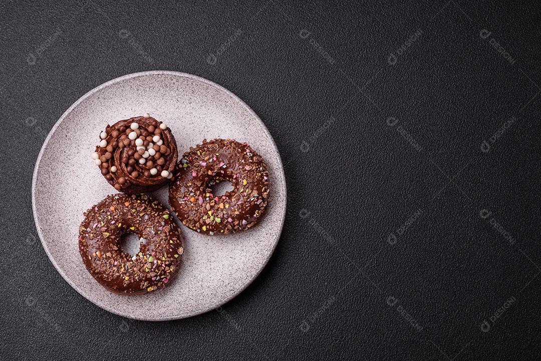 Deliciosos donuts frescos com recheio e cobertura de chocolate sobre um fundo escuro de concreto