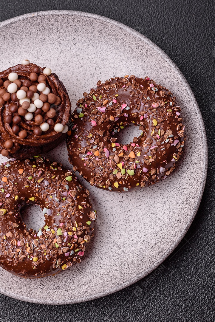 Deliciosos donuts frescos com recheio e cobertura de chocolate sobre um fundo escuro de concreto