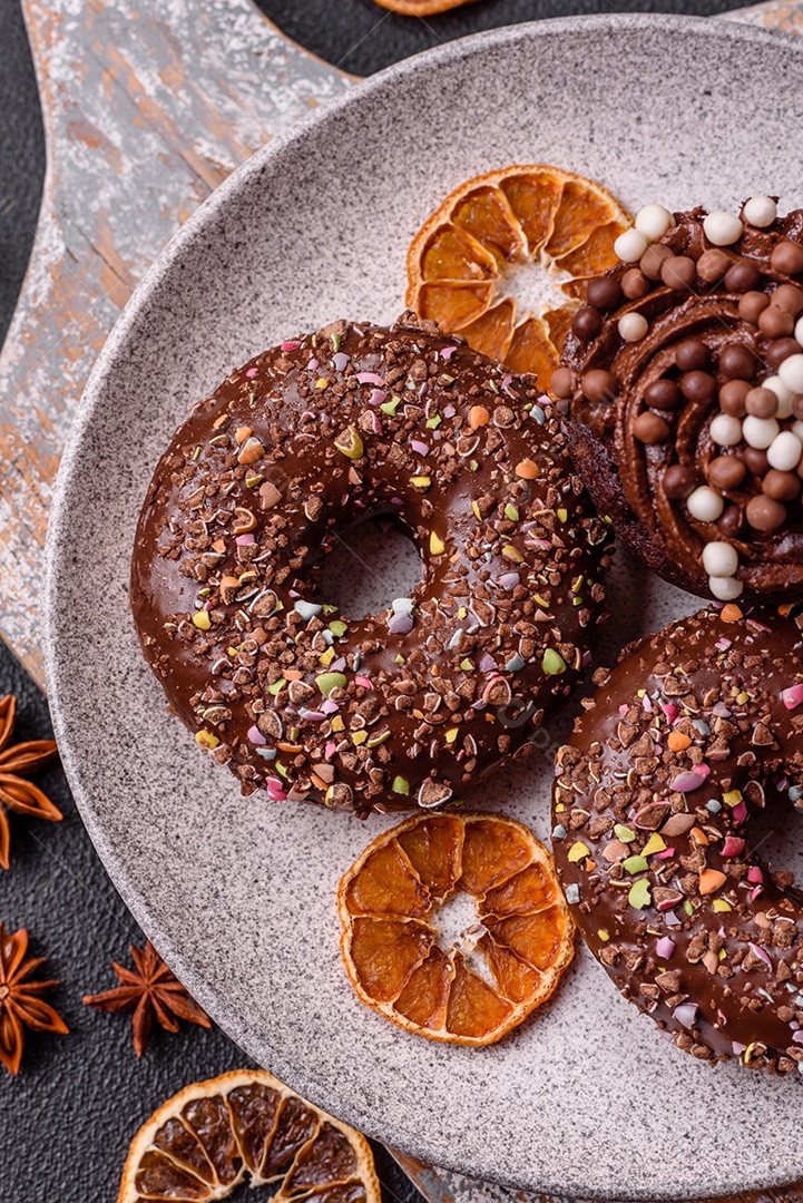 Deliciosos donuts frescos com recheio e cobertura de chocolate sobre um fundo escuro de concreto
