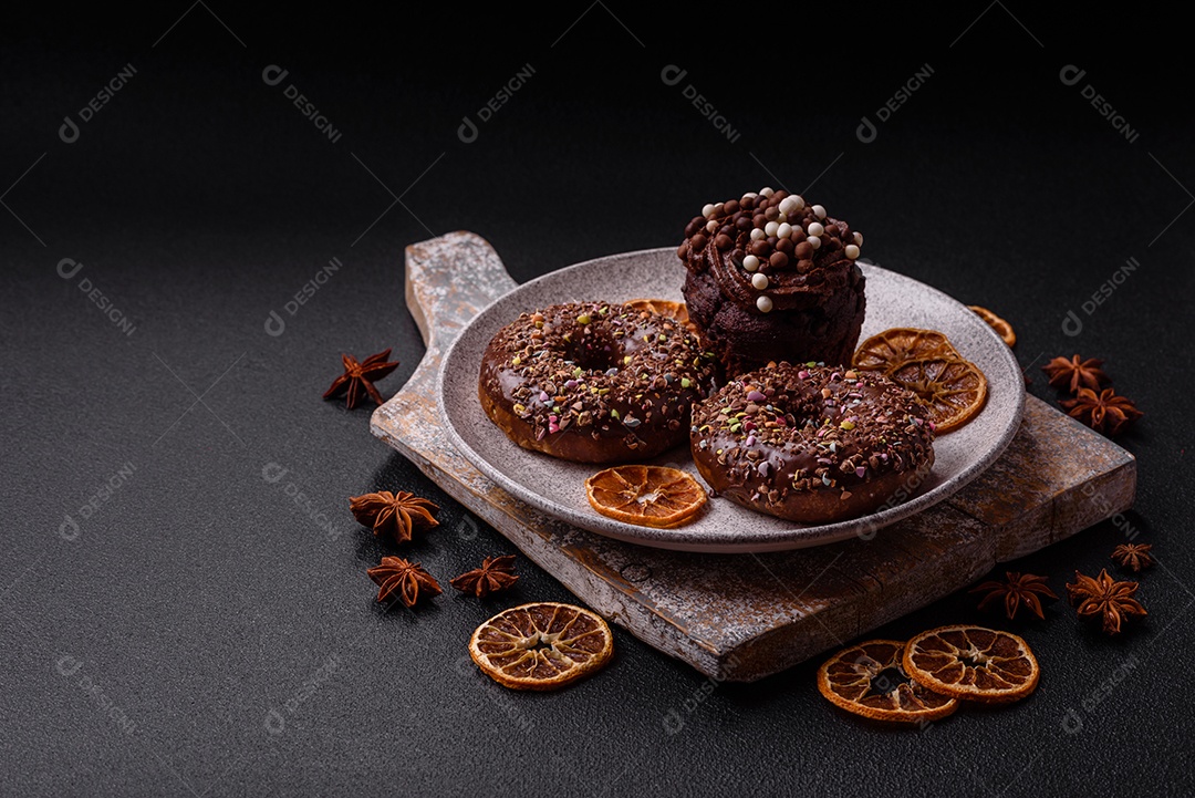 Deliciosos donuts frescos com recheio e cobertura de chocolate sobre um fundo escuro de concreto