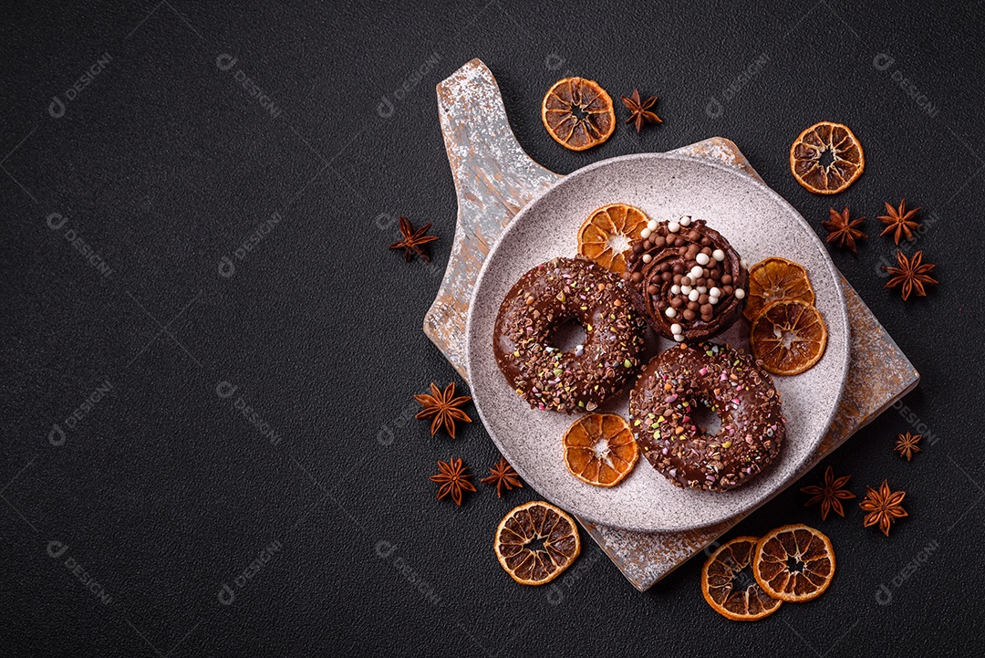 Deliciosos donuts frescos com recheio e cobertura de chocolate sobre um fundo escuro de concreto