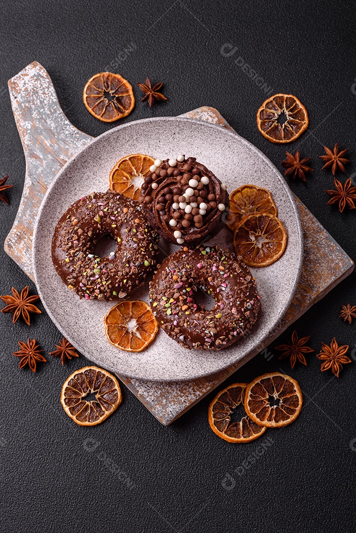 Deliciosos donuts frescos com recheio e cobertura de chocolate sobre um fundo escuro de concreto