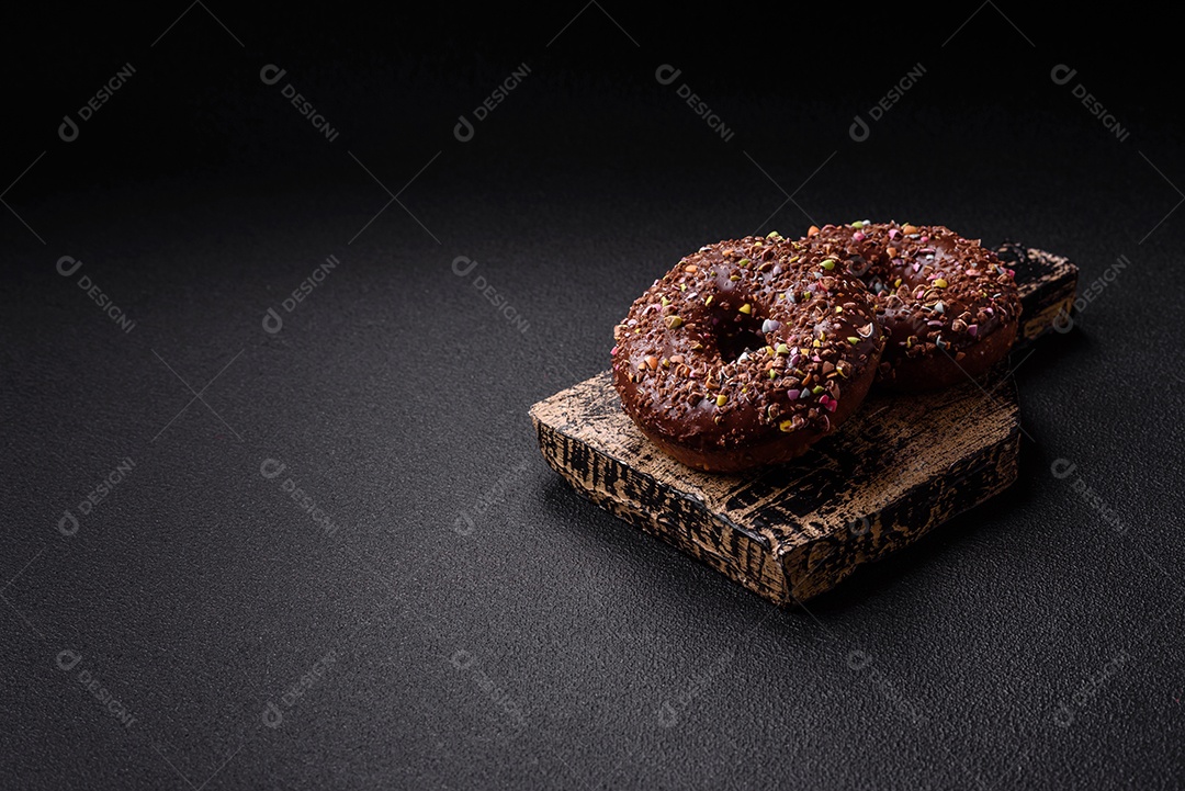 Deliciosos donuts frescos com recheio e cobertura de chocolate sobre um fundo escuro de concreto