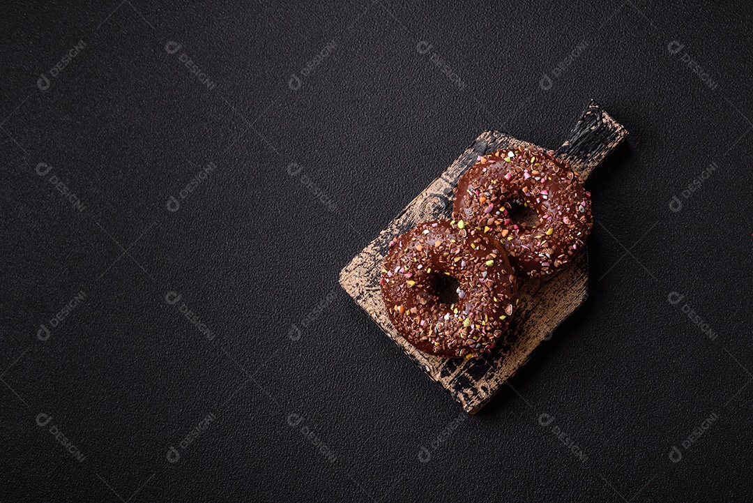 Deliciosos donuts frescos com recheio e cobertura de chocolate sobre um fundo escuro de concreto