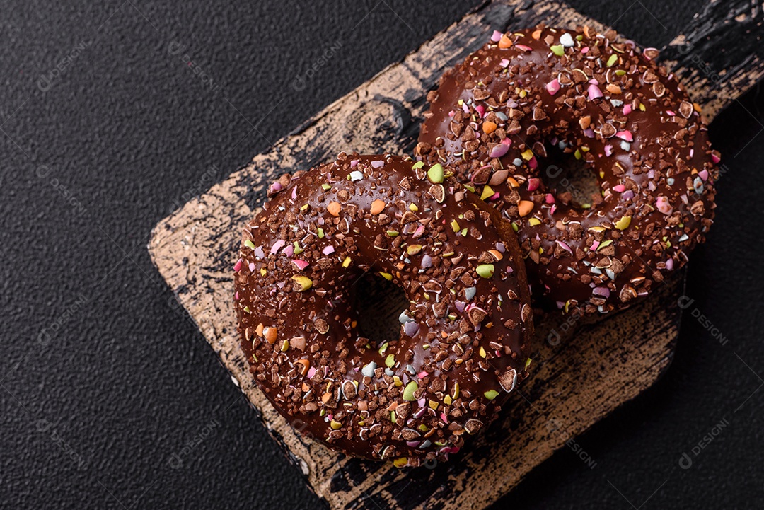Deliciosos donuts frescos com recheio e cobertura de chocolate sobre um fundo escuro de concreto