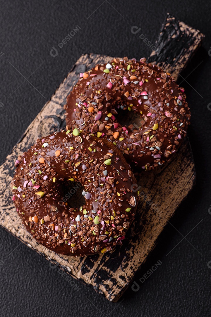 Deliciosos donuts frescos com recheio e cobertura de chocolate sobre um fundo escuro de concreto