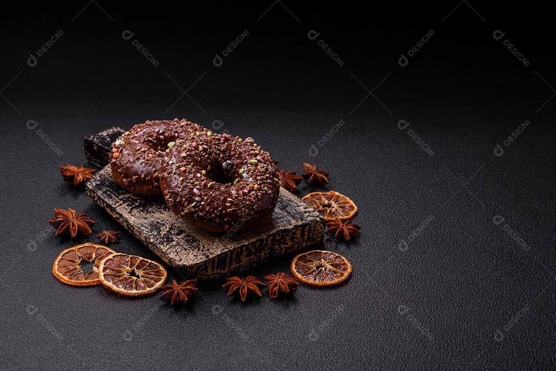 Deliciosos donuts frescos com recheio e cobertura de chocolate sobre um fundo escuro de concreto