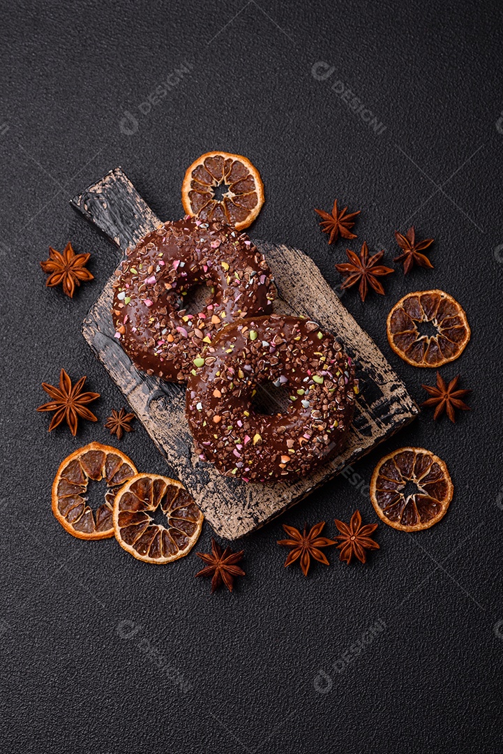 Deliciosos donuts frescos com recheio e cobertura de chocolate sobre um fundo escuro de concreto