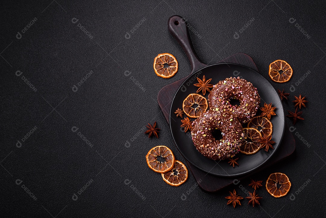 Deliciosos donuts frescos com recheio e cobertura de chocolate sobre um fundo escuro de concreto