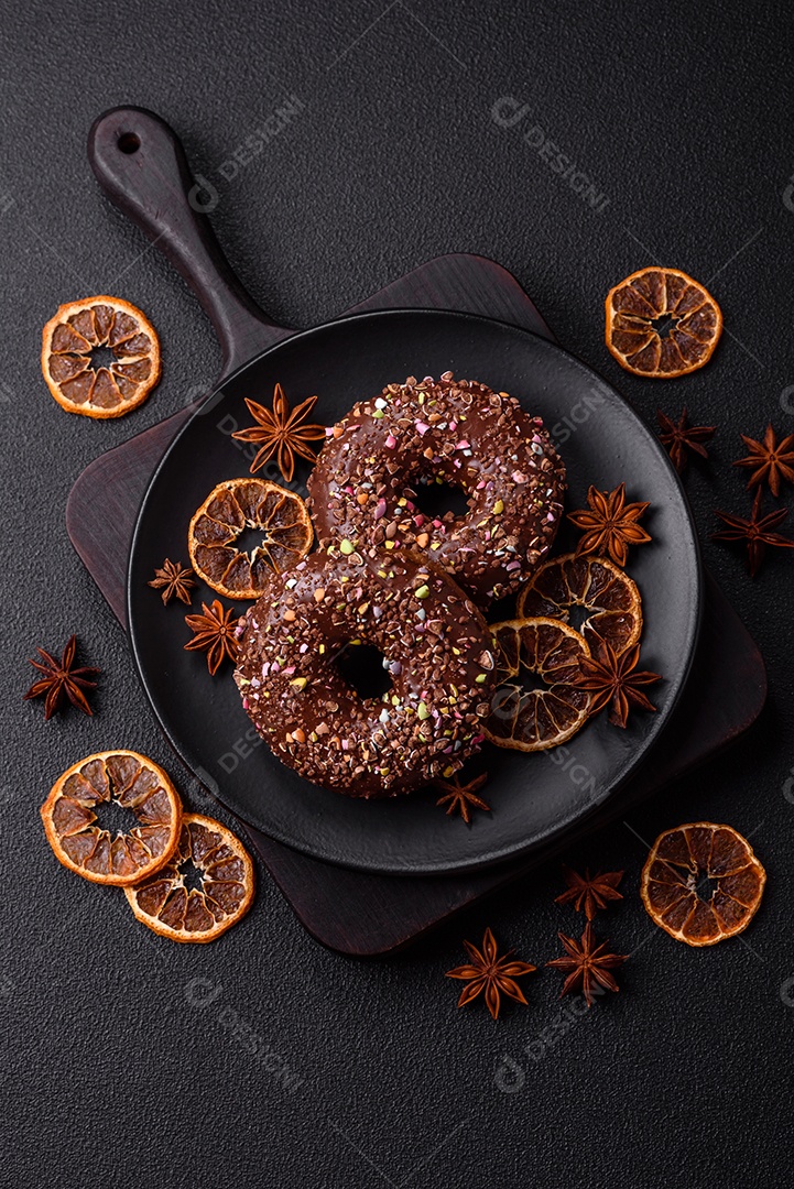 Deliciosos donuts frescos com recheio e cobertura de chocolate sobre um fundo escuro de concreto