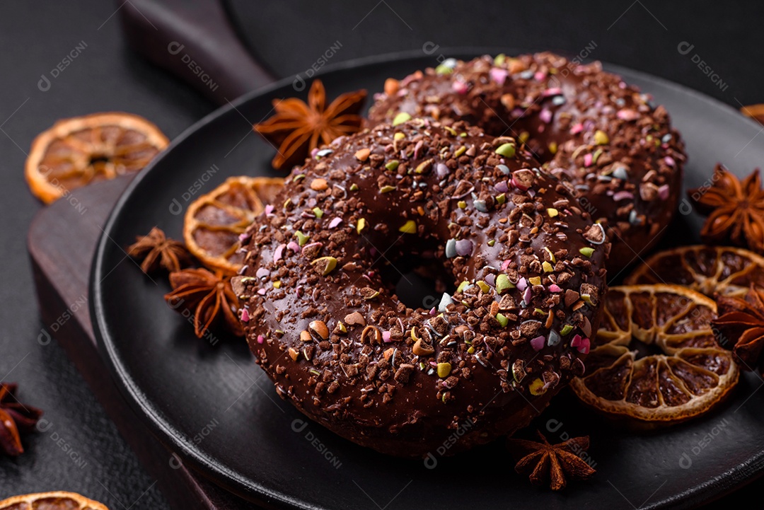 Deliciosos donuts frescos com recheio e cobertura de chocolate sobre um fundo escuro de concreto