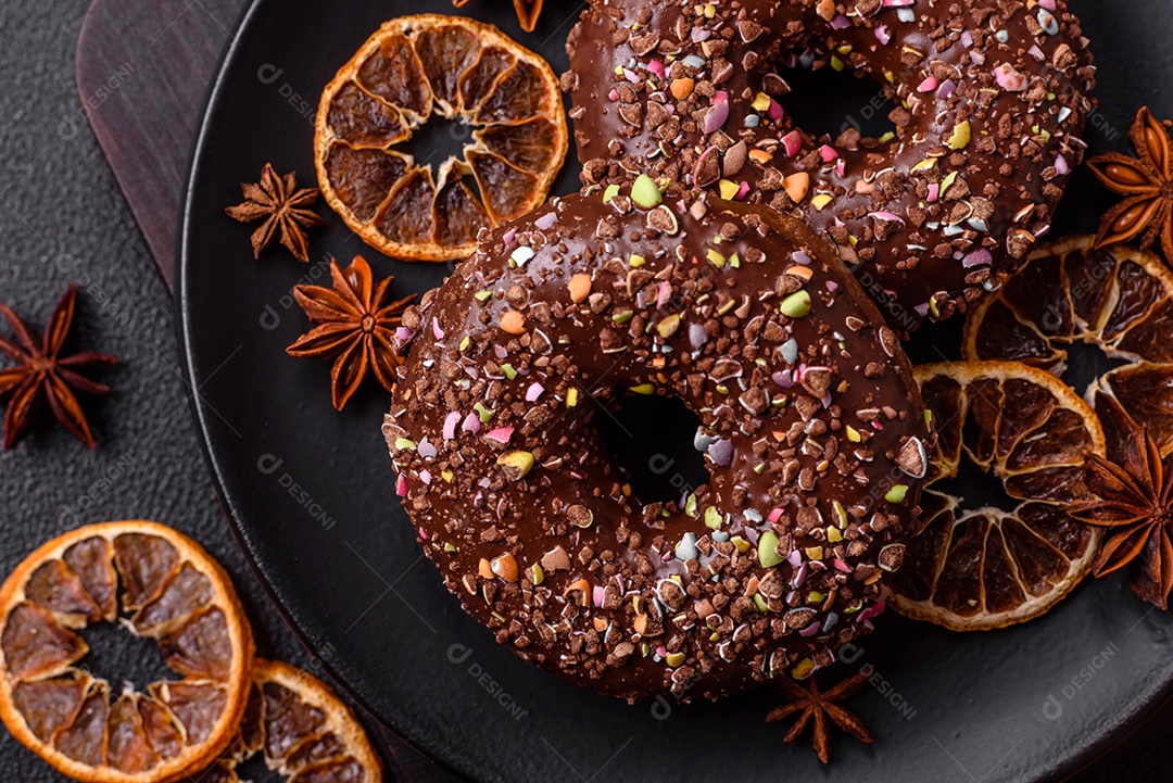Deliciosos donuts frescos com recheio e cobertura de chocolate sobre um fundo escuro de concreto