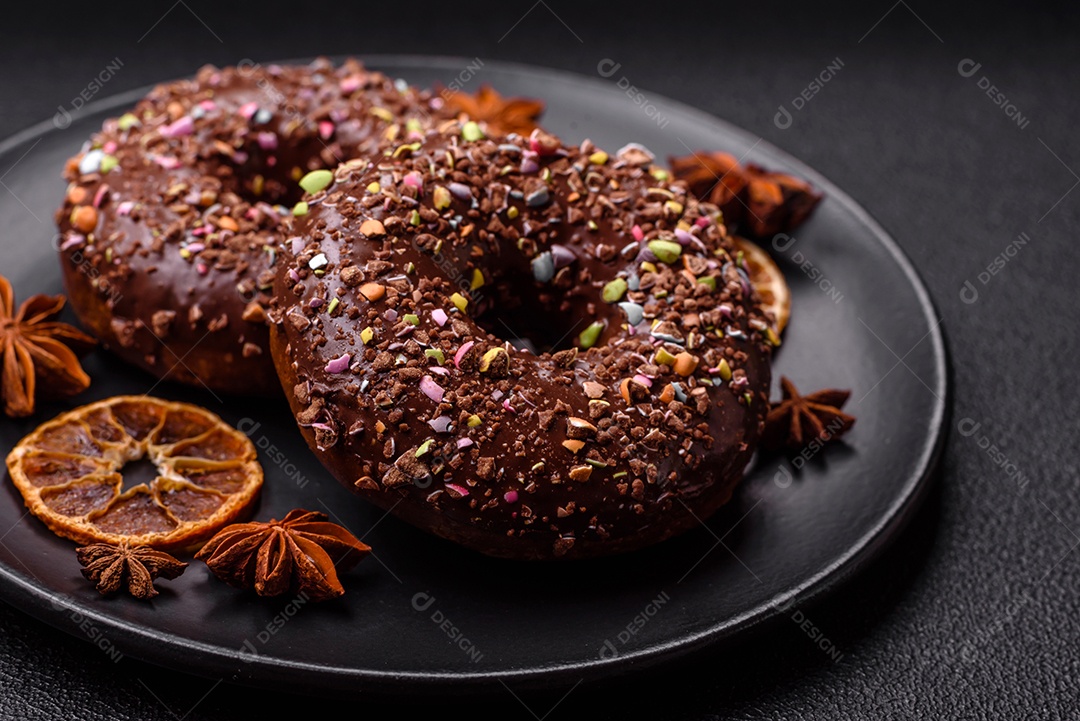 Deliciosos donuts frescos com recheio e cobertura de chocolate sobre um fundo escuro de concreto