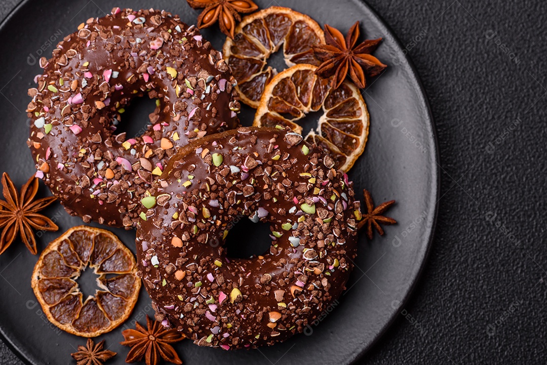 Deliciosos donuts frescos com recheio e cobertura de chocolate sobre um fundo escuro de concreto