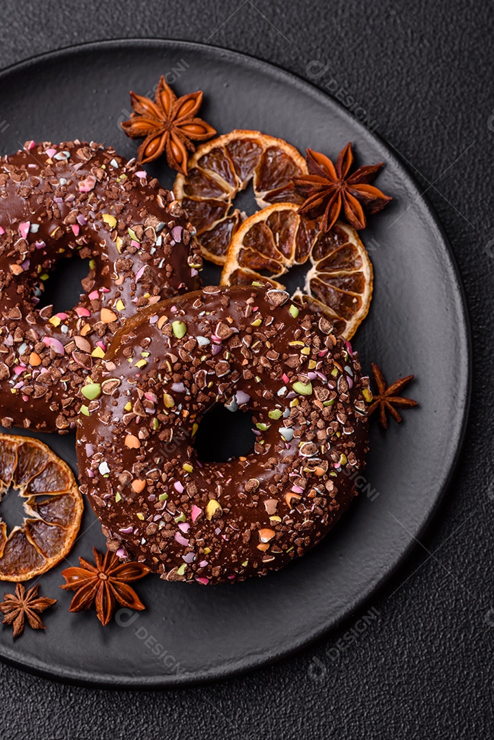 Deliciosos donuts frescos com recheio e cobertura de chocolate sobre um fundo escuro de concreto