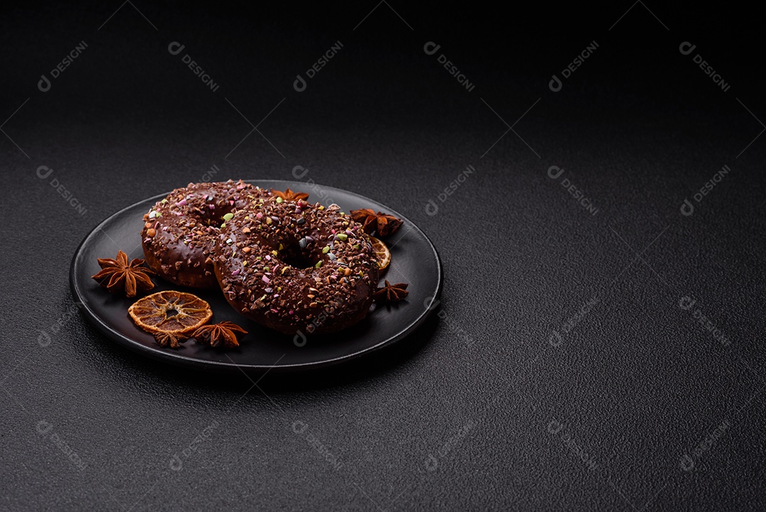 Deliciosos donuts frescos com recheio e cobertura de chocolate sobre um fundo escuro de concreto