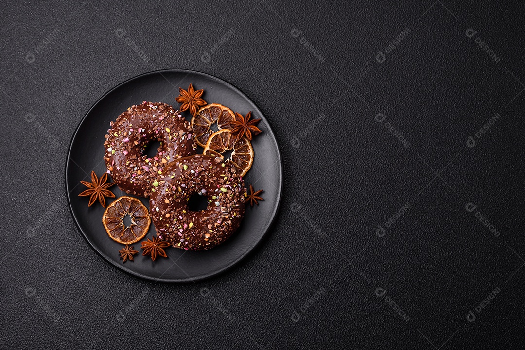 Deliciosos donuts frescos com recheio e cobertura de chocolate sobre um fundo escuro de concreto