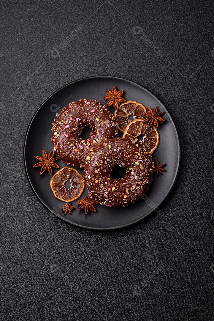 Deliciosos donuts frescos com recheio e cobertura de chocolate sobre um fundo escuro de concreto