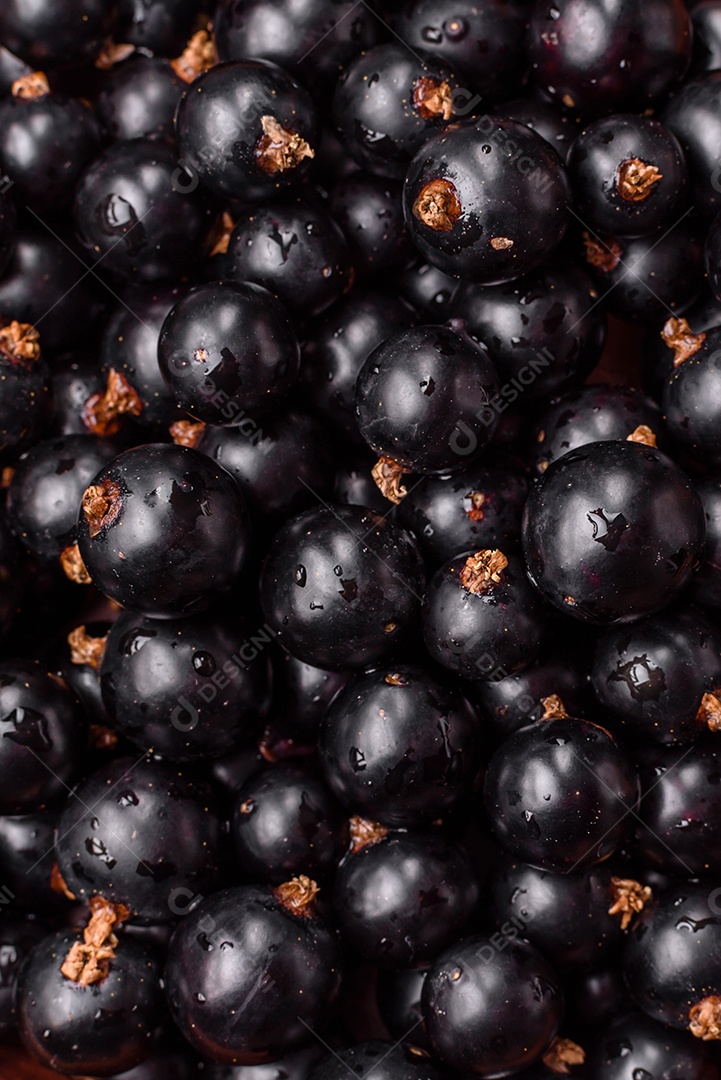 Bagas maduras de groselha preta em gotas de água em uma tigela de cerâmica sobre um fundo escuro de concreto