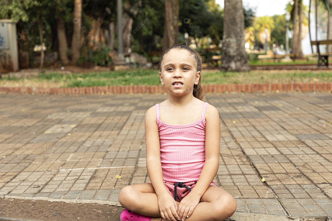 Garotinha sentada olhando para algo