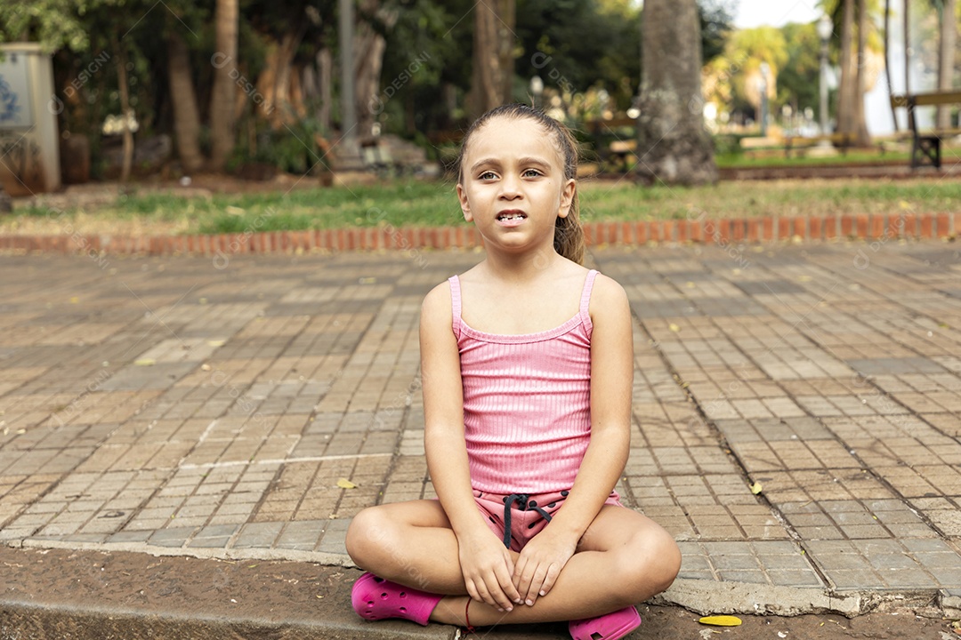 Garotinha sentada com mãos na perna