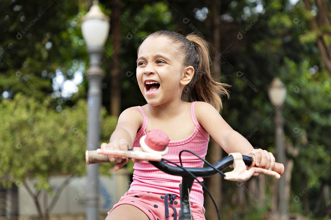 Linda menina feliz andando na sua bicicleta