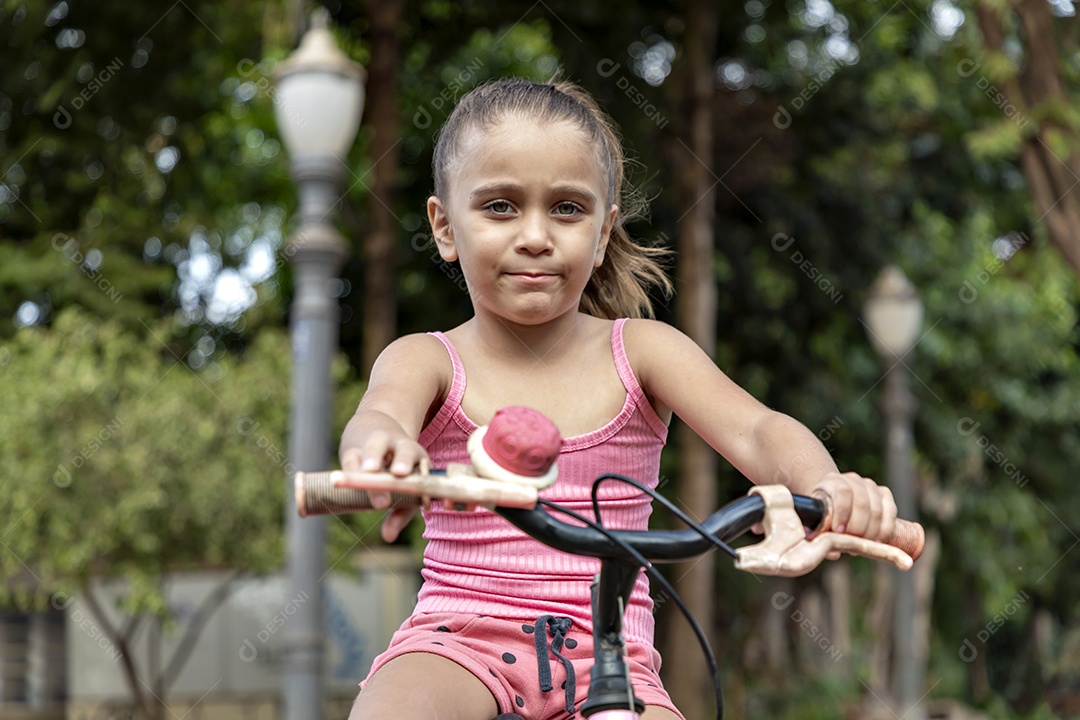 Linda garotinha na sua bicicleta cor de rosa