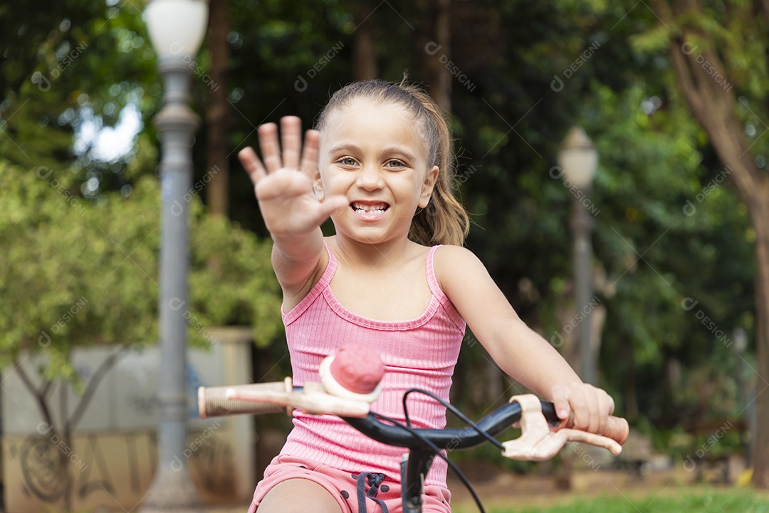 Uma linda garota em sua bicicleta dando tchau