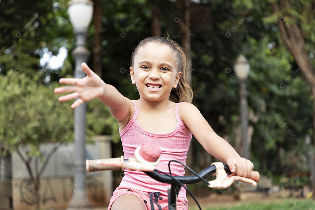 Uma linda garotinha dando tchau andando de bicicleta