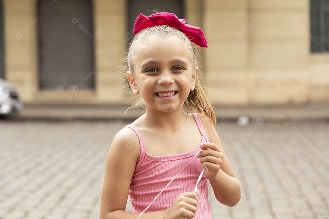 Linda garotinha sorrindo com brinquedo de sabão nas mãos