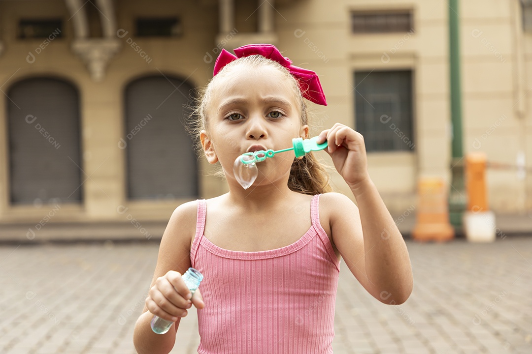 Uma linda garotinha brincando com bolhas de sabão
