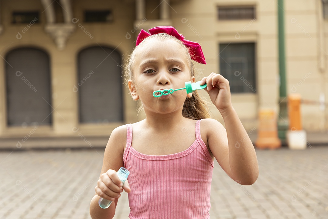 Uma linda garotinha brincando com bolhas de sabão