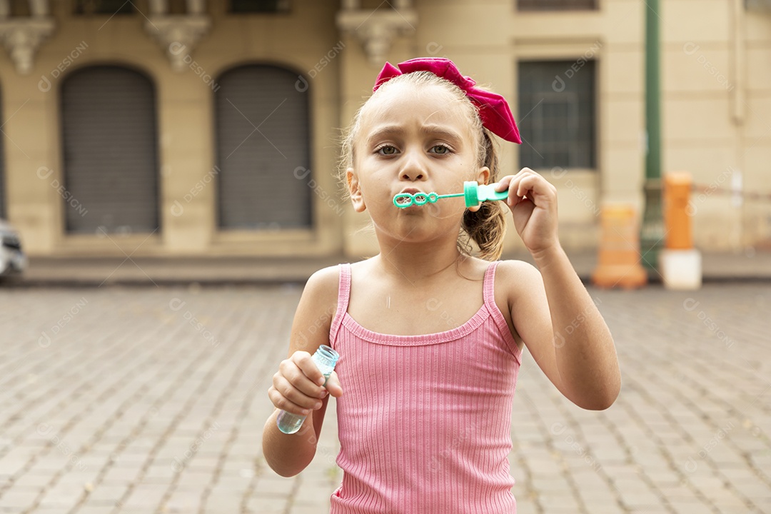 Uma linda garotinha brincando com bolhas de sabão