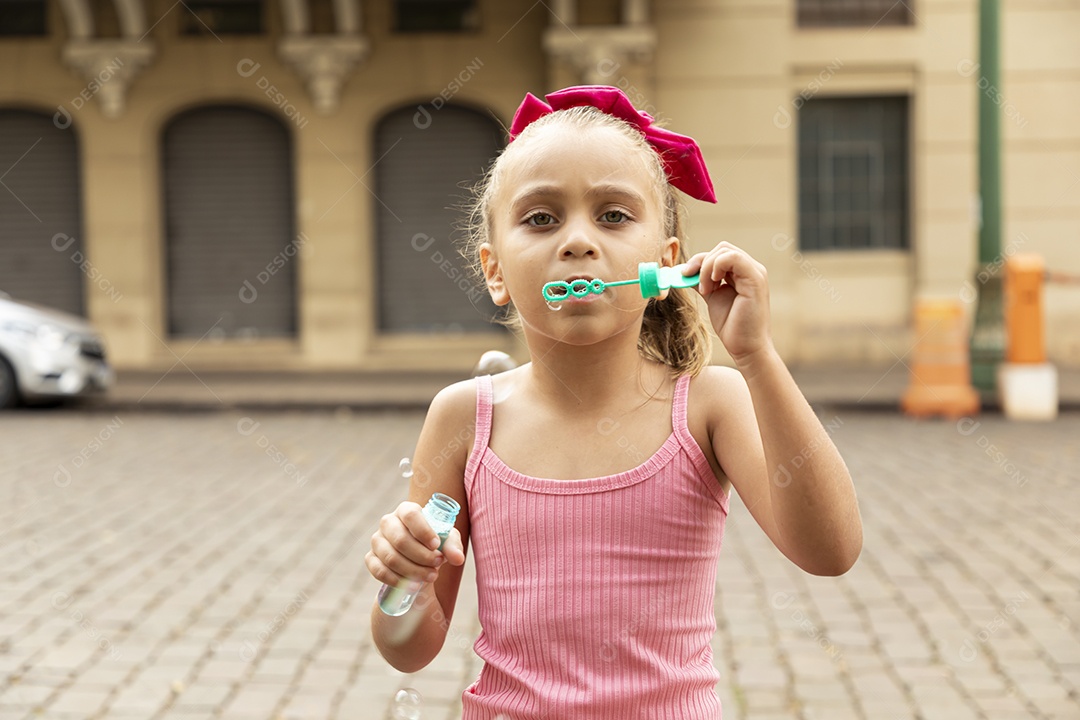Uma linda garotinha brincando com bolhas de sabão