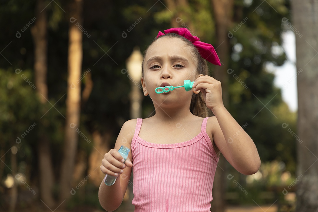 Uma adorável menina brincando no parque com bolhas de sabão