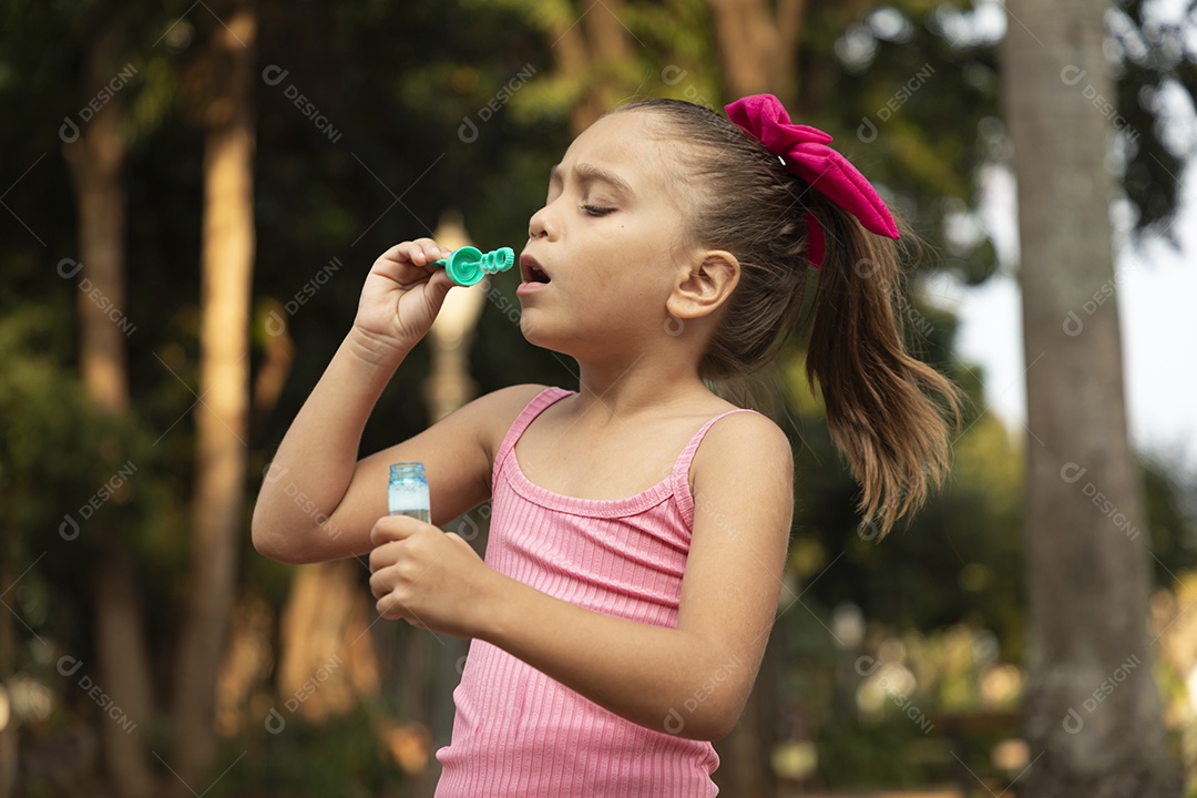 Uma adorável menina brincando no parque com bolhas de sabão