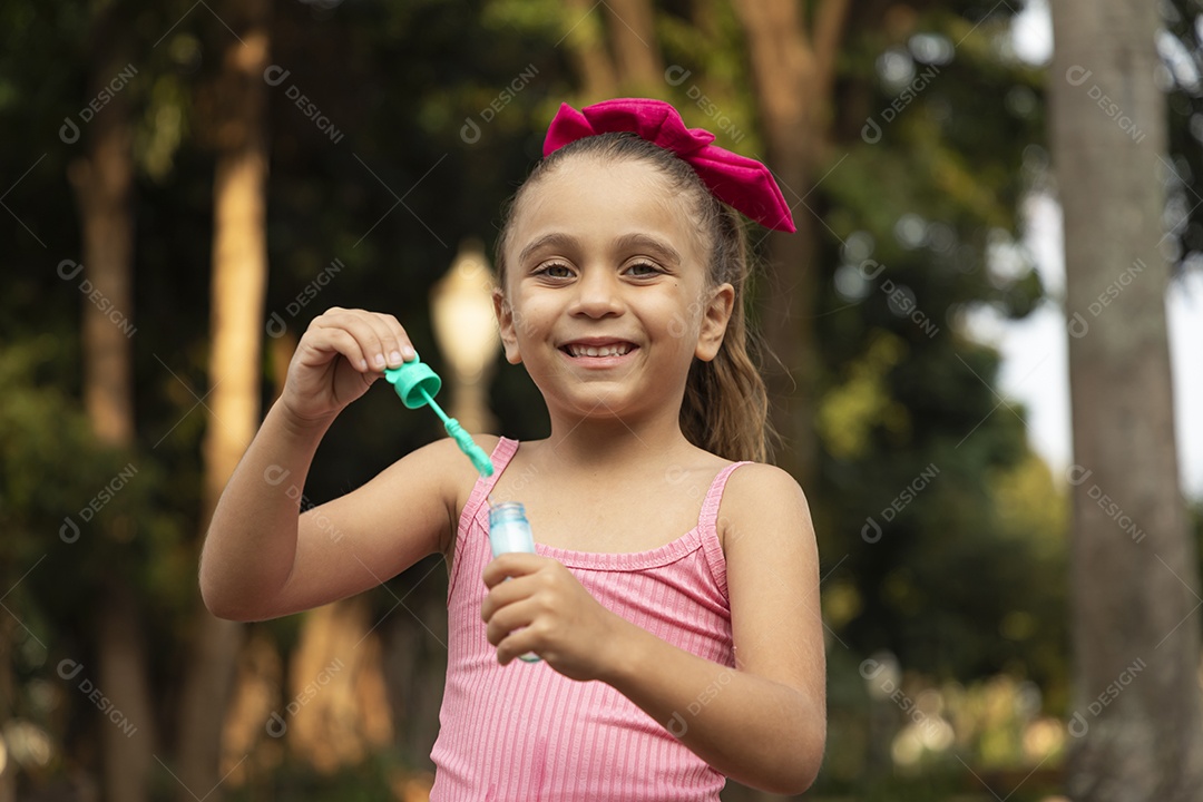 Menina linda sorridente com brinquedo de bolhas nas mãos