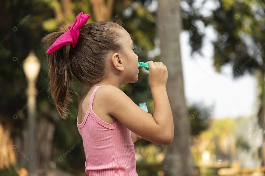 Menina sorridente brincando com bolhas de sabão