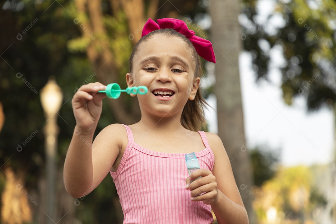 Menina sorridente brincando com bolhas de sabão