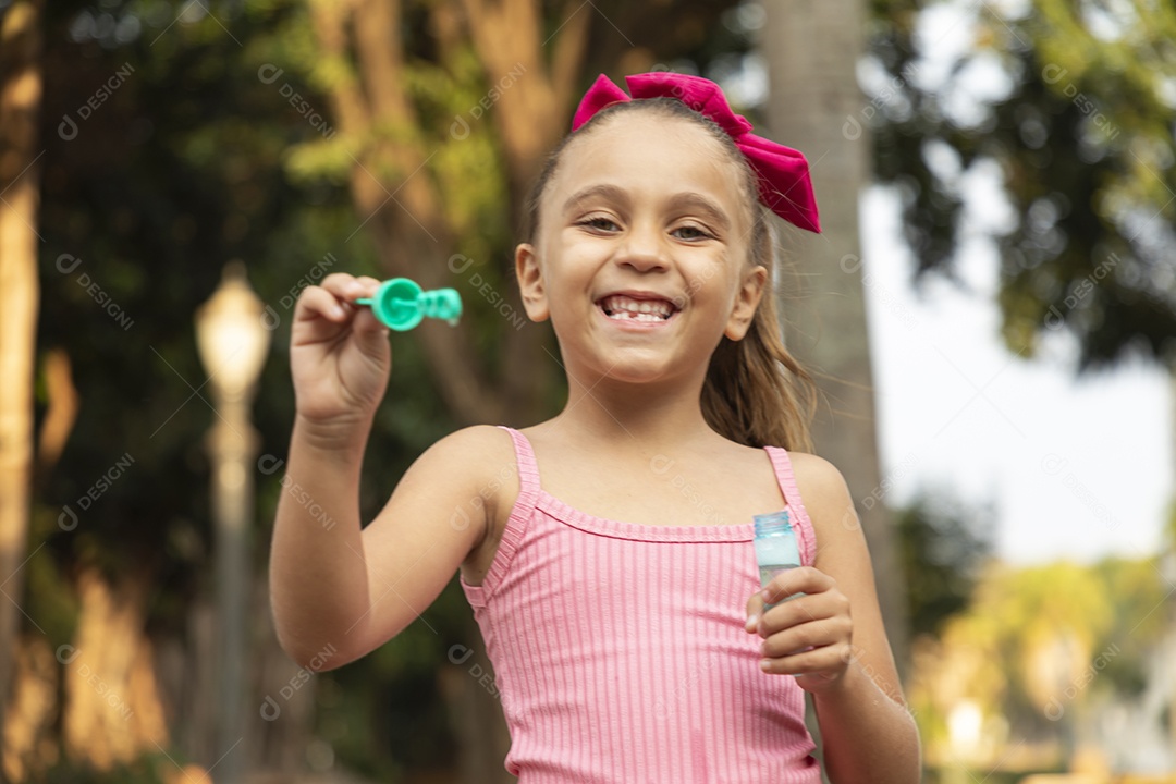 Menina sorridente brincando com bolhas de sabão