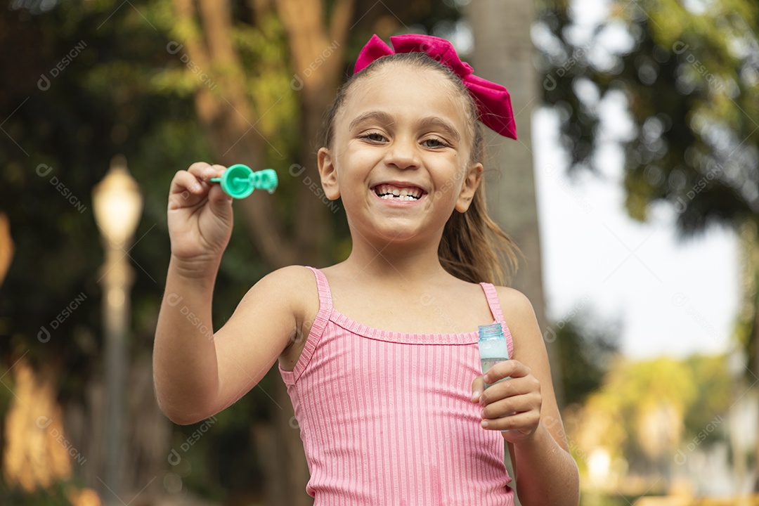 Menina sorridente brincando com bolhas de sabão