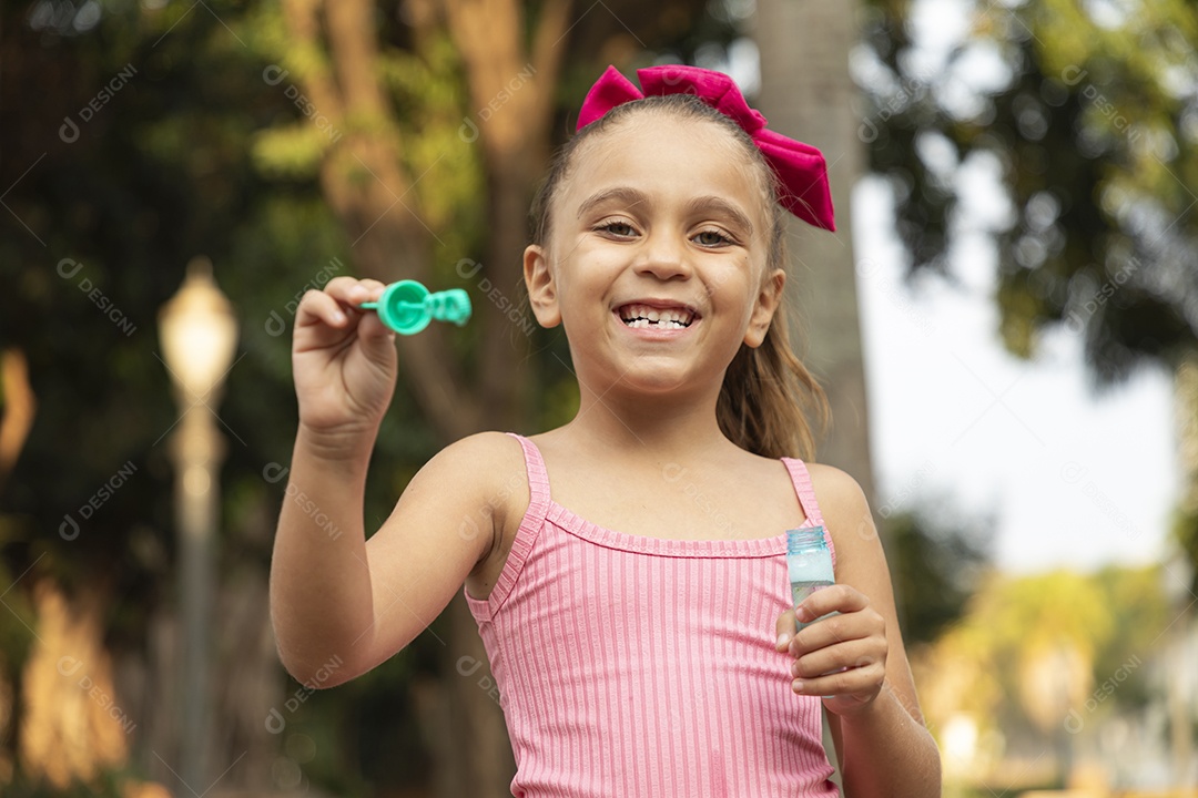 Menina sorridente brincando com bolhas de sabão