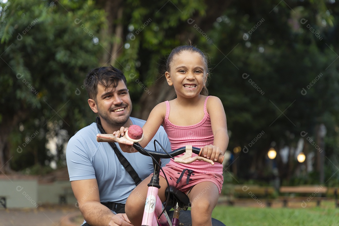 Pai e filha se divertindo de bicicleta no parque