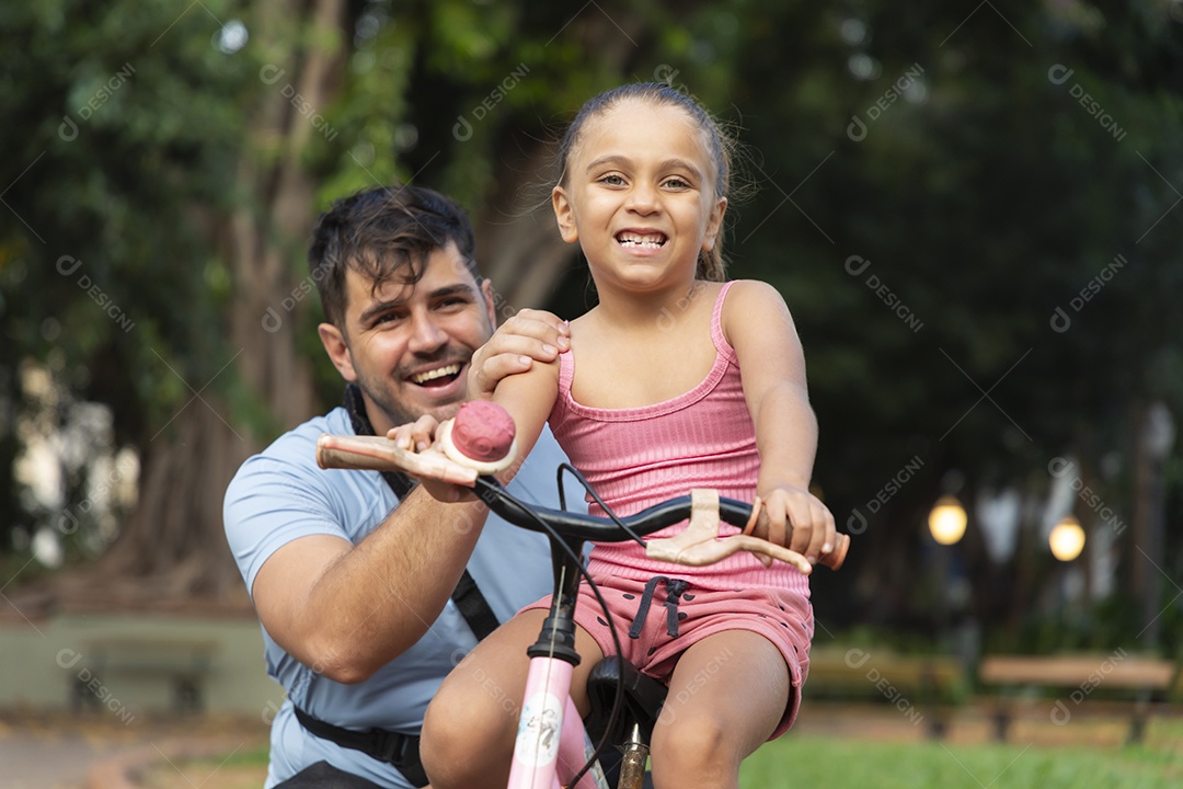 Um pai ensinando a filha andar de bicicleta