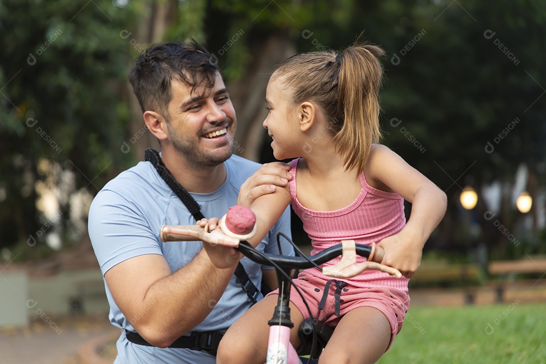 Pai e filha se divertindo de bicicleta no parque