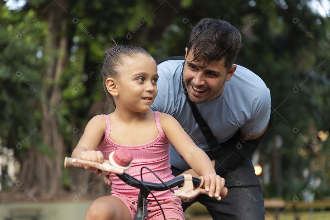 Criança sorrindo brincando de bicicleta com seu pai