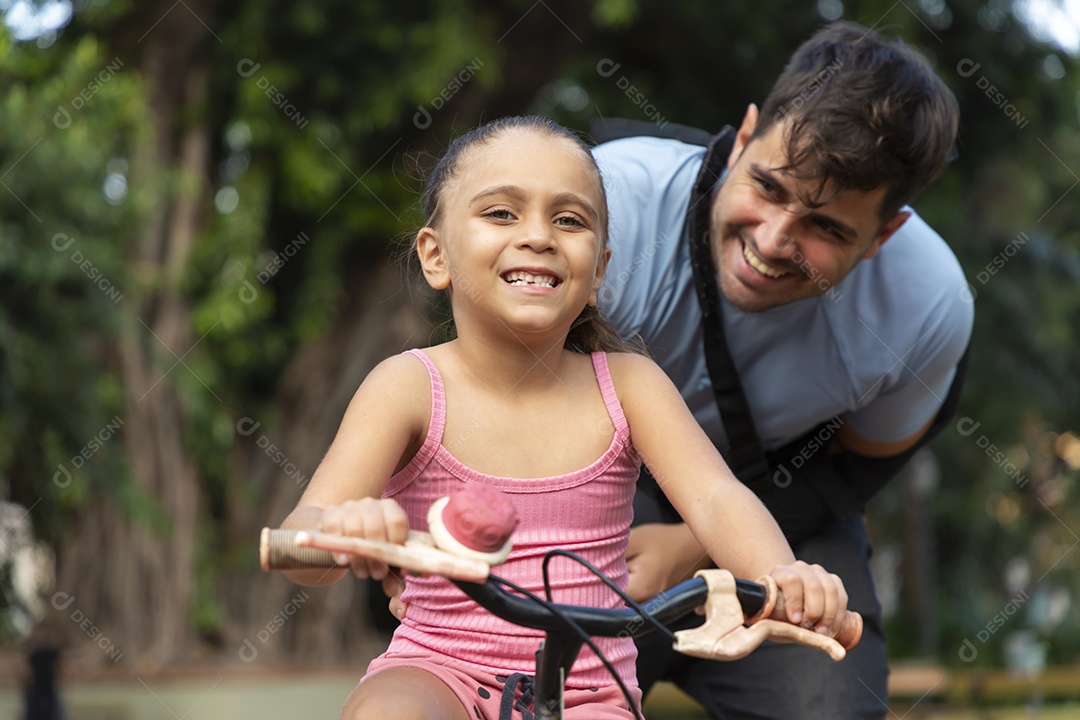 Menina feliz andando de bicicleta com seu pai